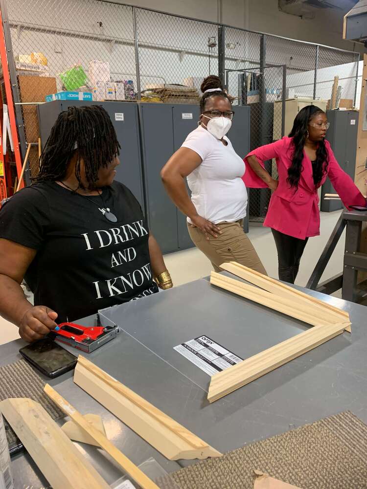 three women posing at a desk and leaning about wood