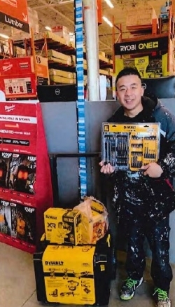 Tony Nguyen holding and standing next to new packages of tools.